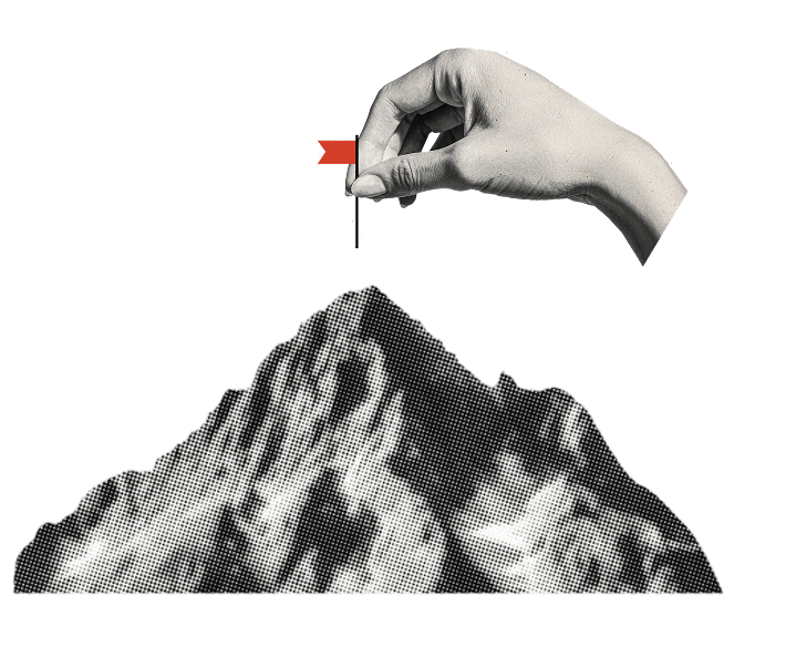 Hand putting small flag on top of a mountain.